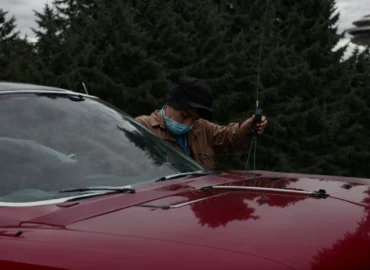 a professional technician repairing a broken windshield on a car parked near seattle's iconic space needle.